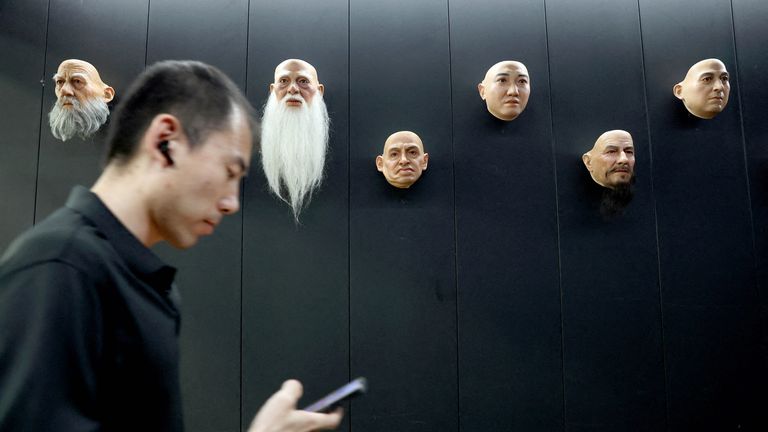 An employee checks his mobile phone as he walks past displays of robot heads, at the office of humanoid robots developer Ex-Robots in Dalian, Liaoning province.
Pic: Reuters