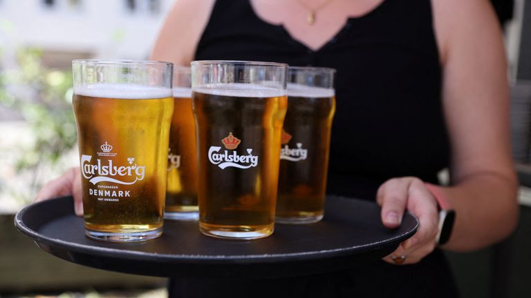 A bar worker carries a tray of Carlsberg beer in Copenhagen, Denmark, July 30, 2022. REUTERS/Andrew Kelly