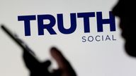 FILE PHOTO: The Truth social network logo is seen displayed behind a woman holding a smartphone in this picture illustration taken February 21, 2022. REUTERS/Dado Ruvic/Illustration/File Photo