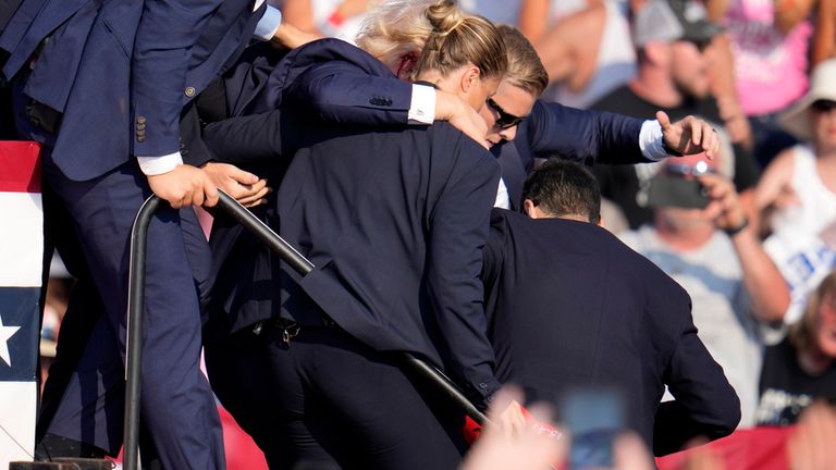 Republican presidential candidate former President Donald Trump is helped off the stage by U.S. Secret Service agents at a campaign event in Butler, Pa., on Saturday, July 13, 2024. (AP Photo/Gene J. Puskar)