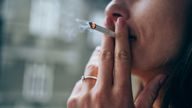 Anonymous young woman enjoying a cigarette outdoors. Focus is on the cigarette. Pic: iStock