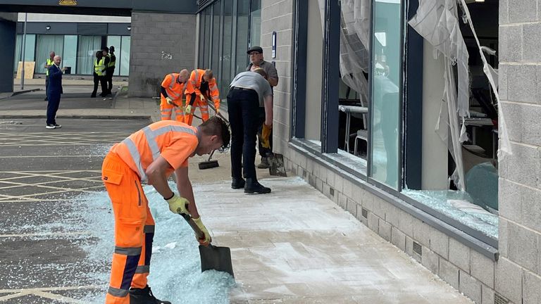 People clear debris at the Holiday Inn Express in Rotherham, South Yorkshire, where anti-immigration rioters smashed the windows before starting fires on Sunday. At least 10 officers were injured, including one who was knocked unconscious, South Yorkshire Police confirmed later, saying one person had already been arrested and others involved should "expect us to be at their doors very soon". Picture date: Monday August 5, 2024. PA Photo. See PA story POLICE Southport. Photo credit should read: Dave Higgens/PA Wire    