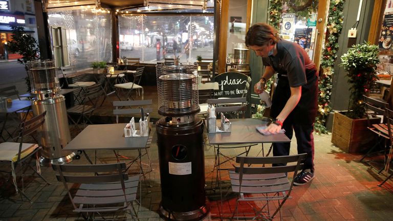 A waiter cleans a table at an empty restaurant which would usually be full of customers, amid the coronavirus disease (COVID-19) outbreak in London, Britain, December 21, 2021. REUTERS/Peter Nicholls