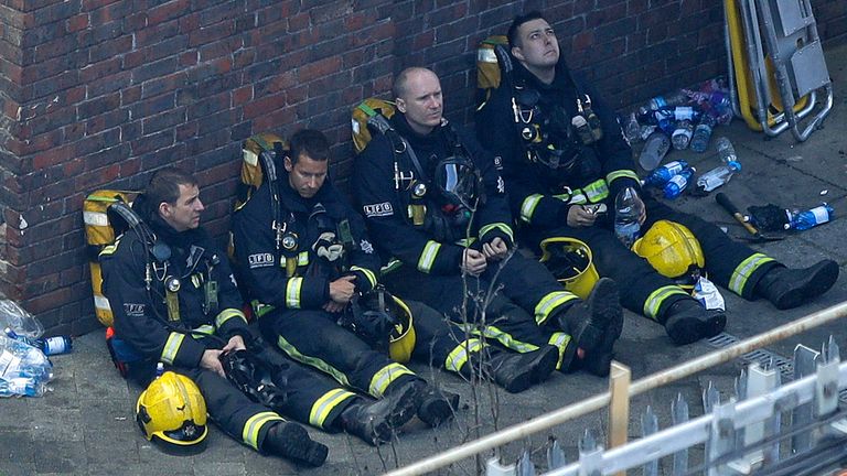 Firefighters rest as they take a break in battling a massive fire that raged in a 27-floor high-rise apartment building in London, Wednesday, June 14, 2017. Fire swept through a high-rise apartment building in west London early Wednesday, killing an unknown number of people and sending more than 50 people to area hospitals. (AP Photo/Matt Dunham)