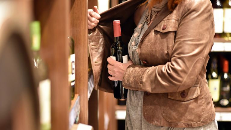 shoplifting - a woman steals a bottle of wine in a supermarket. Pic: iStock