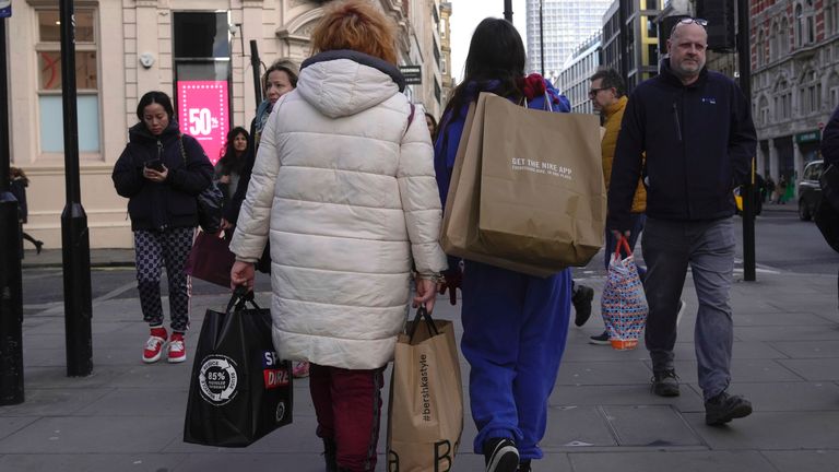 People walk along a street in a shopping district in central London, Friday, Jan. 13, 2023. The U.K. economy grew unexpectedly in November as the tight job market increased demand for employment services and soccer's World Cup boosted hospitality. (AP Photo/Kin Cheung)