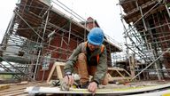 A construction worker uses a tape measure on the construction site of residential buildings in Worcester, Britain December 5, 2024. REUTERS/Temilade Adelaja