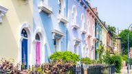 A clear blue summer sky above pastel coloured traditional townhouses in Hammersmith, West London.