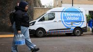 A resident carries bottled water distributed by Thames Water after a pipe burst.