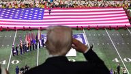 President Trump salutes during the national anthem at the Super Bowl. Pic: Reuters